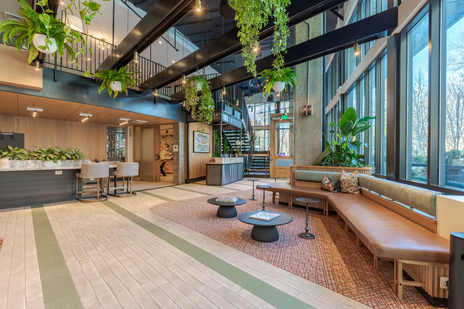 Lobby area in Atwell's luxury apartments in Silver Spring, MD showcasing multiple seating areas and greenery hanging from the roof
